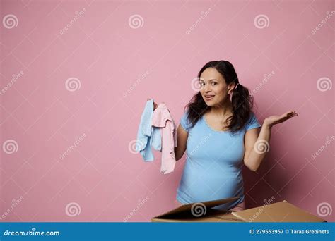 Happy Pregnant Woman With Big Belly Shows Blue Pink Newborn Bodysuit