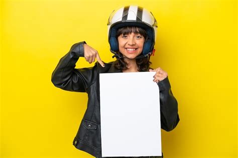 Jovem Mulher Latina Um Capacete De Moto Isolado Em Fundo Amarelo Segurando Um Cartaz Vazio