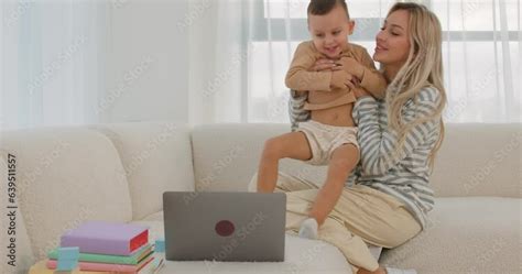Awesome Blonde Mom With Infant Son On Knees Using PC Computer In Living Room Mommy Touching Kid