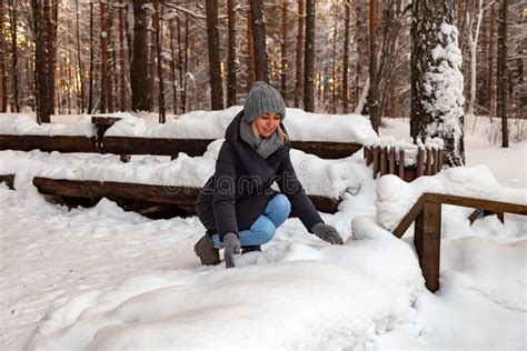 La Fille Blonde Dans Un Chapeau Gris Et Des Gants Et Une Veste D Hiver Se Sont Accroupies Vers