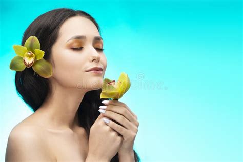 A Beautiful Brunette Nude Shoulders Girl Sensually Holds A Flower Of An Orchid In Her Hands