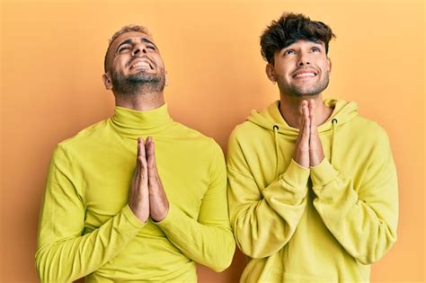 Pareja Gay Homosexual De Pie Juntos Con Ropa Amarilla Rogando Y Rezando Con Las Manos Juntas Con