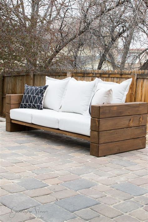 A White Couch Sitting On Top Of A Brick Floor Next To A Wooden Fence