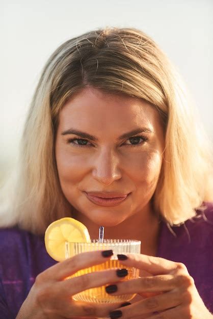 Premium Photo A Beautiful Blonde Woman Enjoys A Cocktail On A Charming Outdoor Terrace