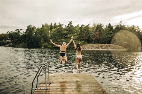 Rückansicht von Freundinnen im Bikini beim Springen im See im Urlaub lizenzfreies Stockfoto