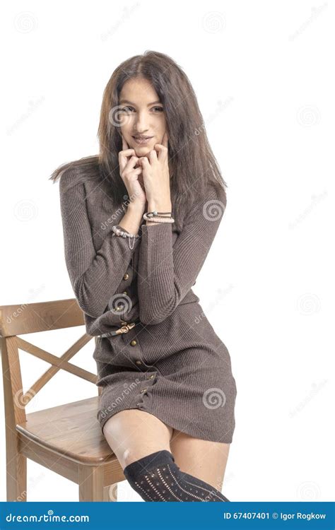 Beautiful Brunette Girl Posing On A Chair In A Long Sweater And Woolen Stockings Stock Image