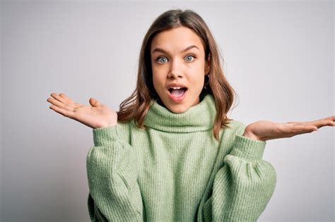 Junge schöne blonde Mädchen in Winterpullover stehen vor isoliertem Hintergrund und feiern