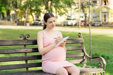 La Mujer Embarazada Se Sienta En Un Banco Del Parque Y Escribe Una