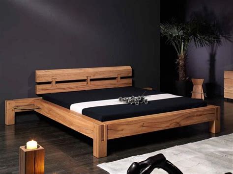 A Wooden Bed Frame With Black Sheets And White Pillows In A Room That