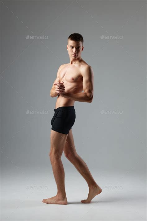 Naked Man In Black Panties On A Gray Background Pumped Up Muscles Of The Torso Barefoot Room