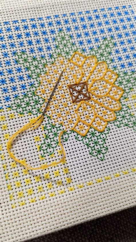 A Close Up Of A Cross Stitch Pattern On A Piece Of Cloth With A Needle