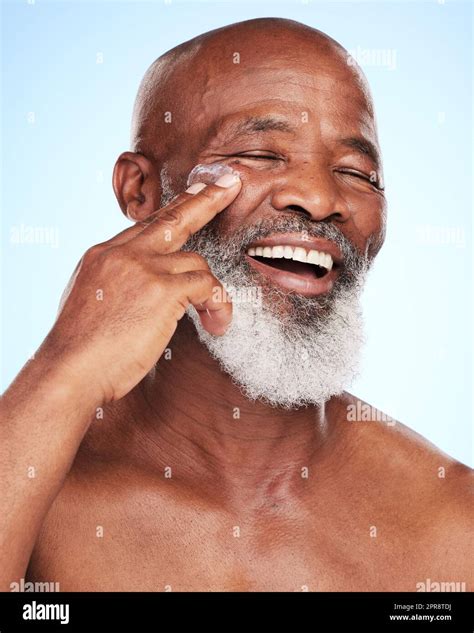 Giving His Skin A Boost A Handsome Mature Man Posing In Studio Against