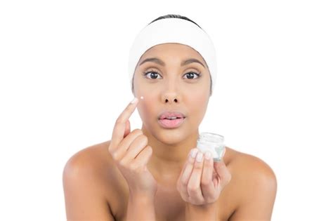 Premium Photo Frowning Nude Brunette Using Moisturizer Looking At Camera