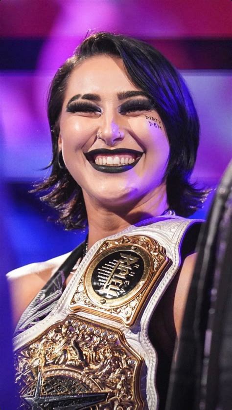 The Woman Is Smiling And Holding Up Her Wwe Championship Belt In Front