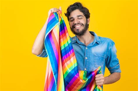 Hombre gay feliz divirtiéndose sosteniendo el símbolo de la bandera del arco iris de la