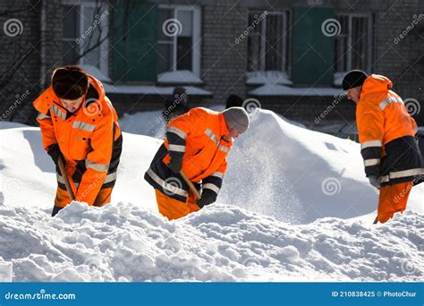 City Utility Workers In Bright Orange Suits Remove Snow From City