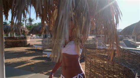 Woman Wearing Bikini Standing Under Straw Canopy Umbrella At The Beach