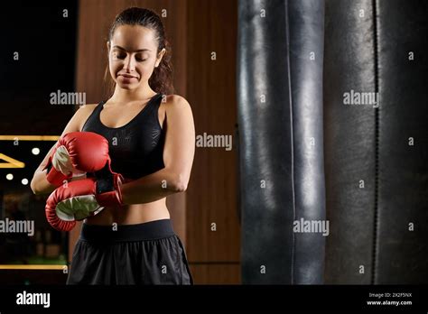 A Brunette Sportswoman In Black Active Wear Throwing Punches With Red Boxing Gloves At A Gym