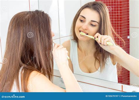 Pretty Funny Girl Brushing Her Teeth In Front Of The Mirror Stock Image