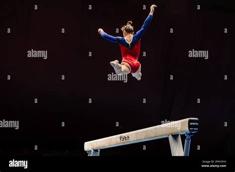 Woman Gymnast Exercise Split Jump In Balance Beam On Black Background