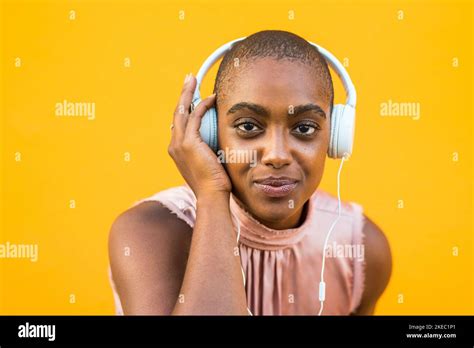 Portrait Of Dark Skinned Woman Listening To Music On Headphones Over