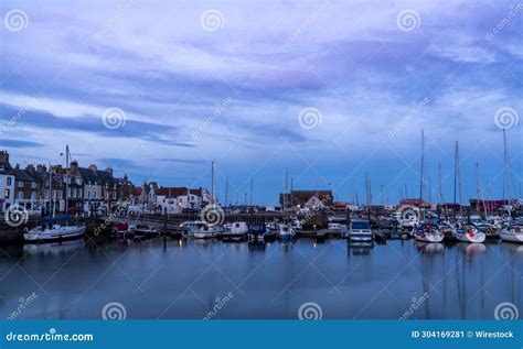 Group Of Boats Peacefully Docked At A Serene Harbor Pier With Buildings