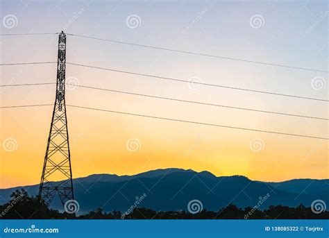 High Voltage Electricity Post In Countryside With Mountain And Sunset