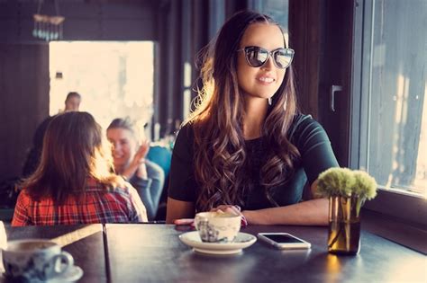 Premium Photo Portrait Of Smiling Brunette Woman In Sunglasses Drinks Morning Coffee In A Cafe