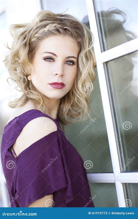 Eine Junge Blonde Frau Mit Dem Gelockten Blonden Haar Und Den Blauen Augen Vor Einem Fenster