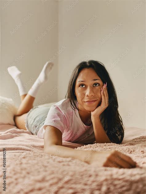 Joven transgénero latina pensativa posando con la mano en el rostro en su habitación Stock Photo
