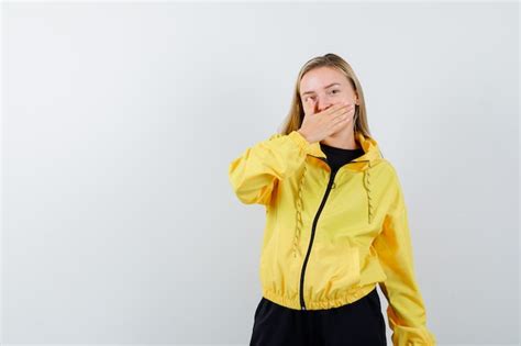 Dame Blonde Gardant La Main Sur La Bouche En Survêtement Et à La Confiance Vue De Face Photo