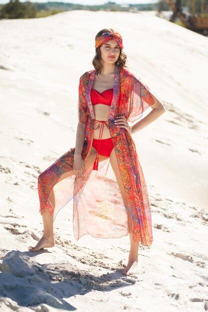 Eine Frau in einem roten Bikini steht am Strand und trägt einen roten Bikini Premium Foto