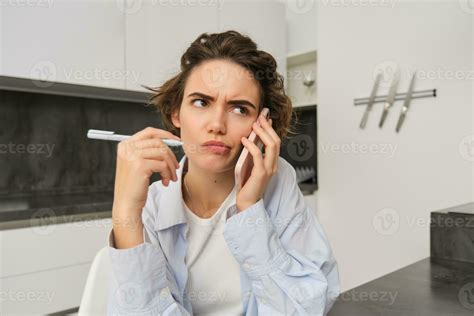 Portrait of woman having complicated conversation, holding smartphone