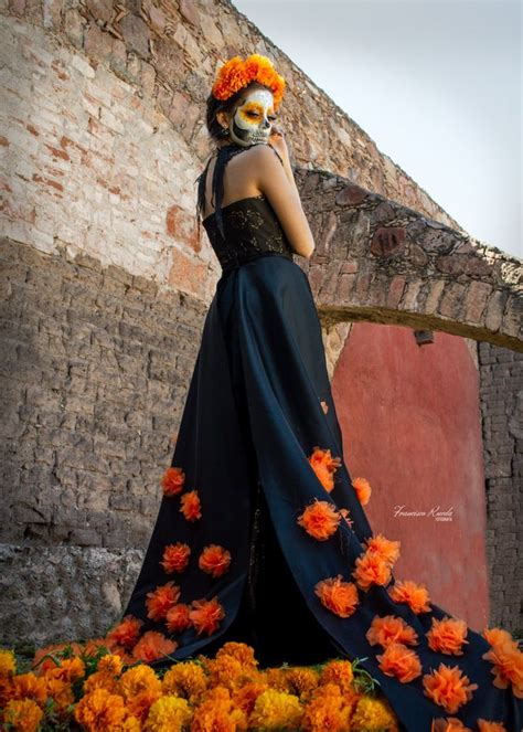 A Woman In A Black Dress With Orange Flowers On Her Head Standing Next