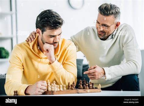 Son And Mature Father Playing Chess Together On Weekend At Home Stock Photo Alamy
