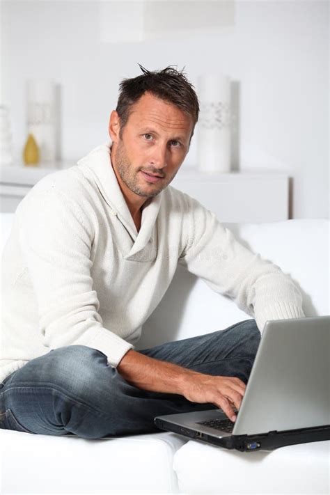 Portrait Of Man Sitting In Sofa With Laptop Stock Photo Image Of