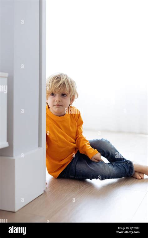 Barefoot Curious Boy With Blond Hair Wearing Casual Clothes Sitting