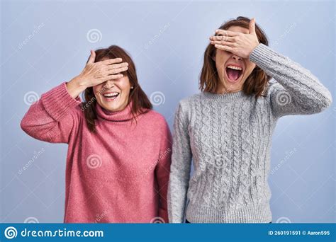 Mother And Daughter Standing Over Blue Background Smiling And Laughing