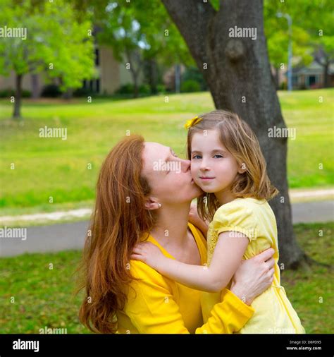Mère embrassant sa fille blonde en plein air du parc vert habillé en jaune Photo Stock Alamy