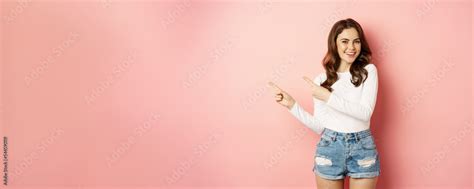 Cute Smiling Brunette Girl Showing Advertisement Pointing Fingers Left At Banner Logo On