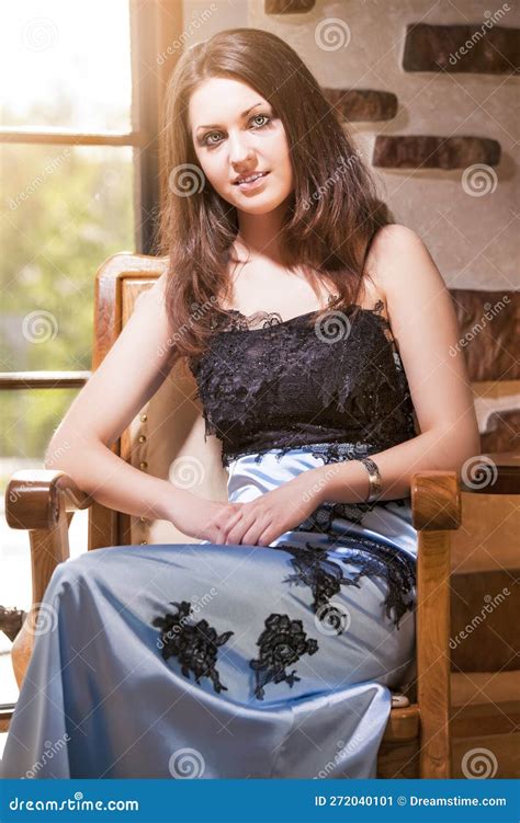 Portrait Of Sensual Caucasian Brunette Female In Long Blue Dress Posing Against Big Window On