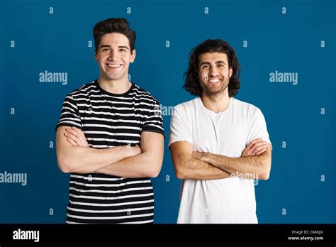 White Brunette Two Men Looking And Smiling At Camera Isolated Over Blue Background Stock Photo