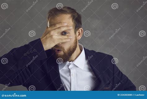 Man Covering Face And Looking Between Fingers Embarrassed By Awkward Situation At Work Stock