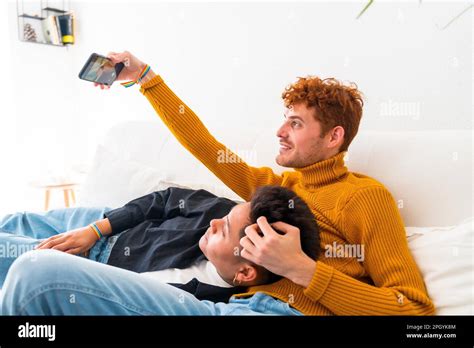 Beautiful Gay Couple Being Romantic Indoors At Home On The Sofa Gay Couple Taking Selfie Lgbt