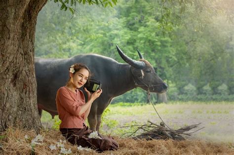 Premium Photo Women Sitting Under Tree Against Buffalo In Rural Fields