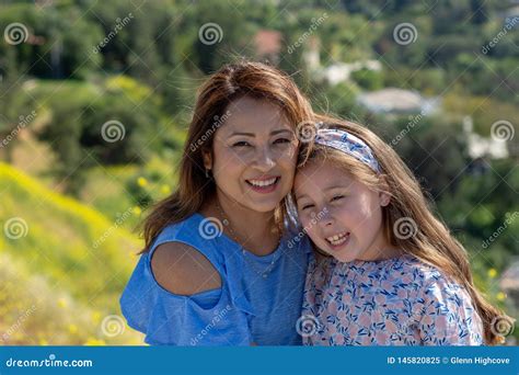 Madre E Hija De Latina Que Sonr En Y Que R En En Una Colina Delante De Las Flores Amarillas