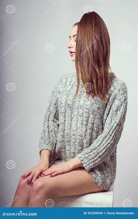 Una Ragazza Si Siede Su Un Cubo Ha Messo Le Sue Mani Sulle Sue Ginocchia Nude In Un Maglione