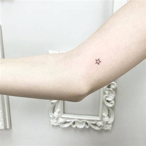 a small star tattoo on the left arm is shown in front of a white frame