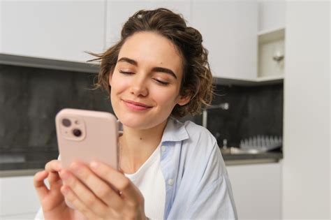 Premium Photo Portrait Of Modern Brunette Woman Holding Mobile Phone And Smiling Girl Sits In