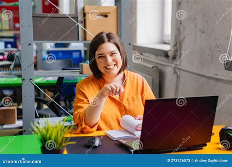 A Brunette Woman In An Orange Blouse Works On A Laptop At Desk In The Office Stock Image Image